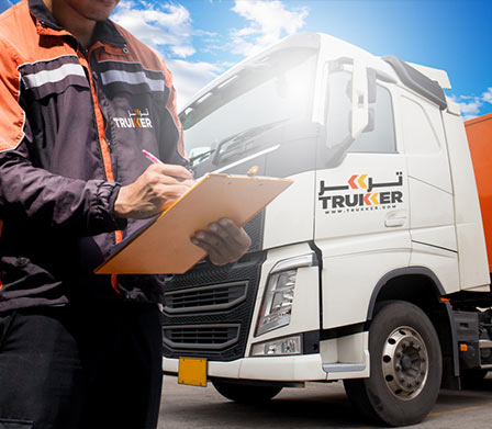 man writing on clipboard in front of a Truker truck