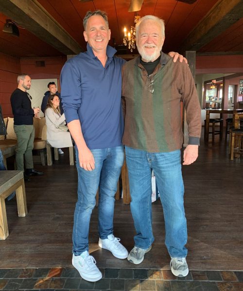 two men standing, smiling for a photo